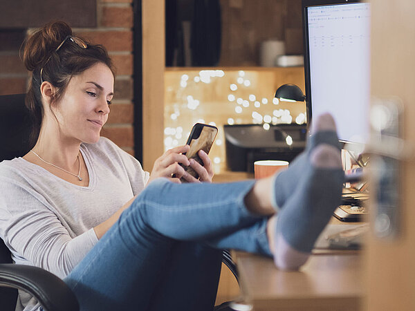 Eine Architektin informiert sich am Smartphone über die SocialMedia-Aktivitäten von Tobias Stahl